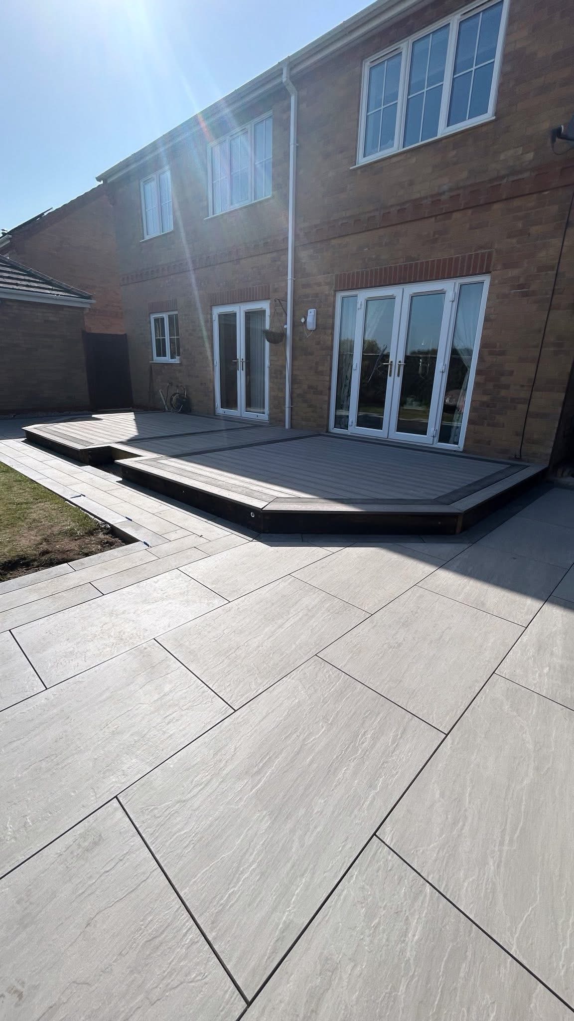 Wide view of grey patio paving and raised decking
